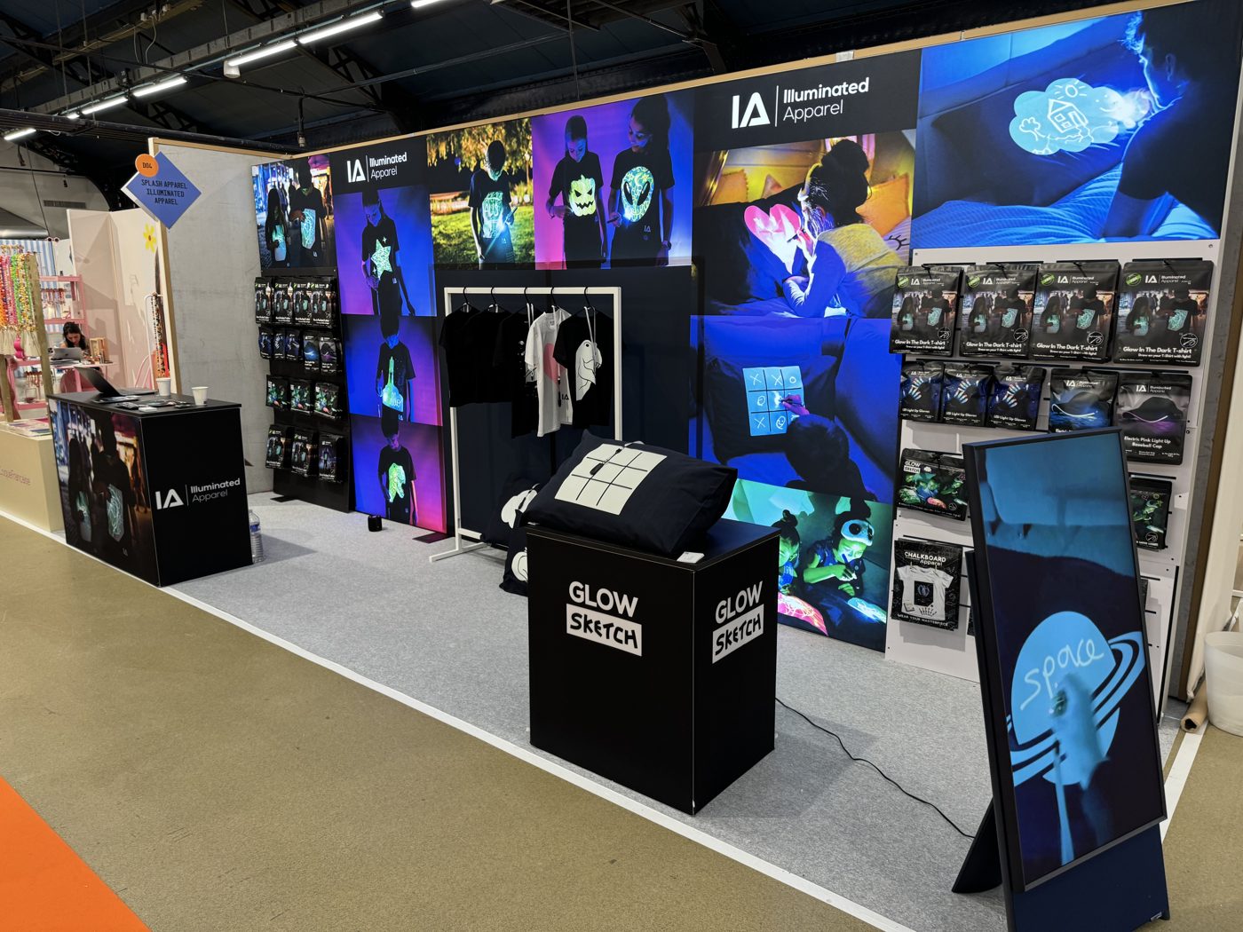 Illuminated Apparel trade show stand with glow T-shirts, Glow Sketch pillowcases, light-up accessories and video screen